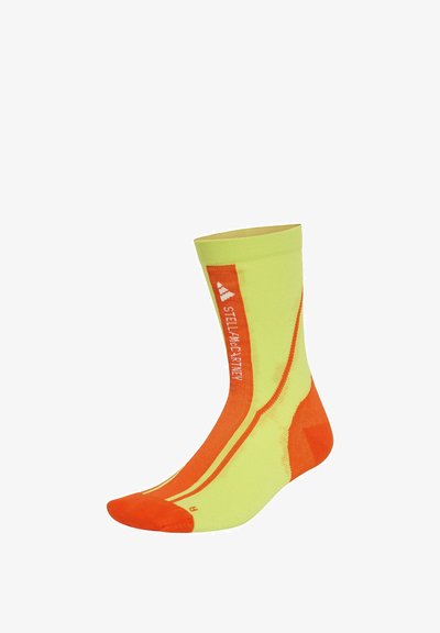 Løbesokker i klart gult og orange. Lavet af åndbart materiale med forstærket tå og hæl, prydet med reflekterende detaljer og branding.