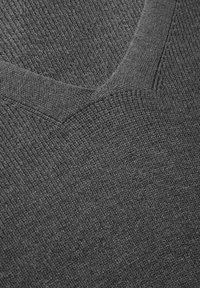 Grau gestrickter Pullover mit V-Ausschnitt. Der strukturierte Stoff hat ein weiches, dichtes Gewebe mit subtilen Farbvariationen.