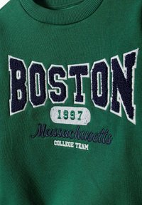 Roheline sweatshirt, millel on sinise ja valge kirjaembrodeeritud tekst "BOSTON" ja "Massachusetts", aastaarv "1997" rohelisega. Pehme tekstuur.