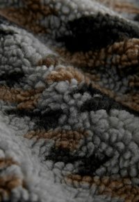 Textured fabric showcasing a mix of gray, brown, and black colors in a soft, fuzzy pattern, with a plush, looped construction.