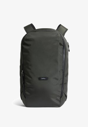 Sac à dos Bellroy vert foncé avec bretelles rembourrées, devant incurvé et poches zippées latérales sur fond blanc.