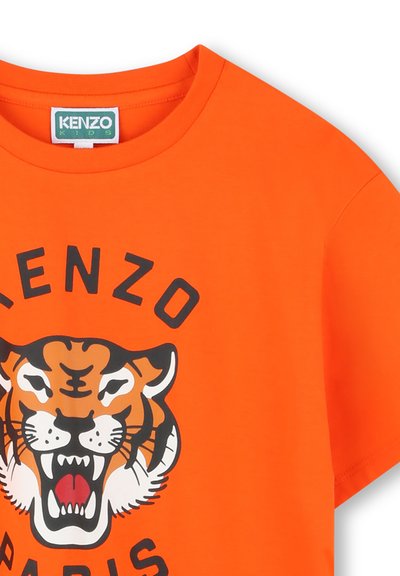 T-shirt en coton orange avec un imprimé graphique de tigre noir et orange, avec les textes "KENZO" et "PARIS" en lettres majuscules. Manches courtes.