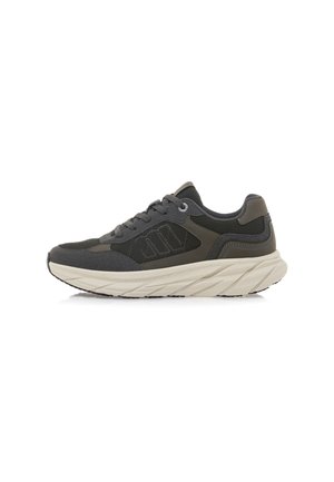 Zapatilla gris con tela texturizada y superposiciones suaves. Presenta una suela gruesa y ondulada en color blanco sucio, y cordones para el cierre.
