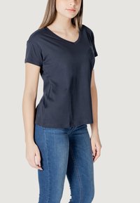 Maglietta a maniche corte V-neck di colore blu navale in tessuto morbido, con un taglio rilassato e una texture liscia, abbinata a un paio di jeans azzurri.