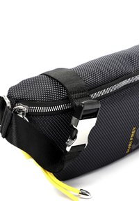 Borsa nera strutturata con una cerniera argentata, cordino giallo in contrasto e una tracolla nera regolabile con chiusura argentata e dettaglio del logo.