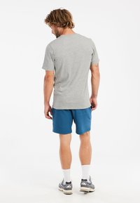 Grå kortærmet t-shirt parret med blå shorts. Outfittet har en afslappet pasform og er lavet af lette materialer.