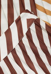 Tissu rayé marron et crème avec des plis, présentant une texture lisse et un doux éclat. L'accent inclut une rayure dorée contrastante.