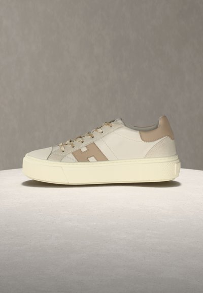 Κλασικό μπεζ και λευκό αθλητικό παπούτσι με κορδόνια, ταμπά τακούνι και μπεζ λωρίδα στο πλάι πάνω σε υπόλευκη ελαστική σόλα.