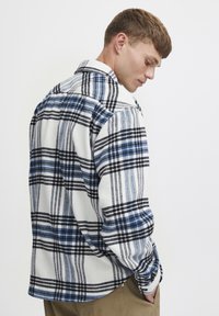Kariertes Flanellhemd in Weiß, Blau und Schwarz. Mit Kragen und langen Ärmeln, aus einem weichen, texturierten Stoff. Gesäumter Saum.