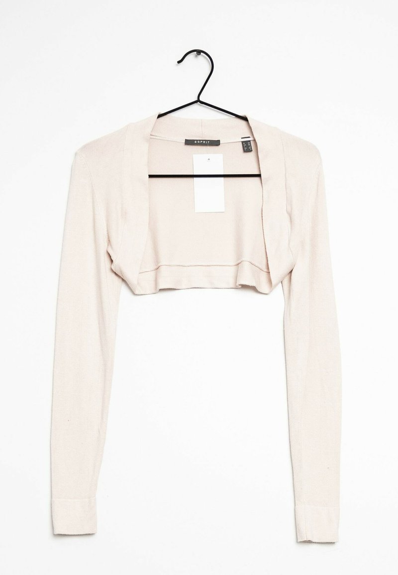 Lyhyt, vaaleanbeige neuletakki pehmeästä kankaasta, jossa on pitkät hihat ja avonainen malli. Roikkuu mustassa koukussa.