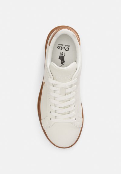 Λευκό δερμάτινο αθλητικό παπούτσι με ταμπά λαστιχένια σόλα. Διαθέτει στρογγυλεμένη μύτη, επίπεδα λευκά κορδόνια και λογότυπο τυπωμένο μαύρο στο πάτο.