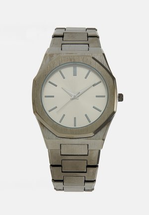 Montre en métal avec un boîtier octogonal en argent, un cadran argent clair, des index horaires argentés et un bracelet en acier inoxydable.