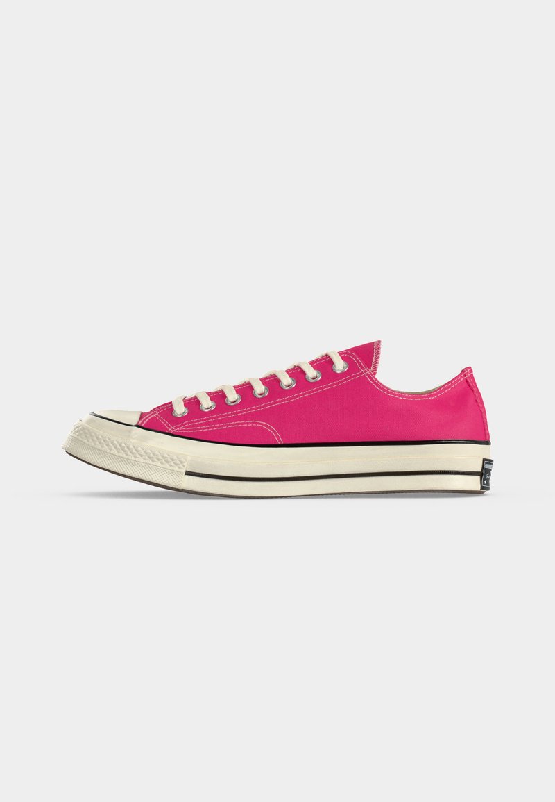 Low-Top Freizeit-Sneaker aus leuchtend pinkem Canvas mit weißen Schnürsenkeln und dicker weißer Sohle mit schwarzen Streifen, seitlich gezeigt.