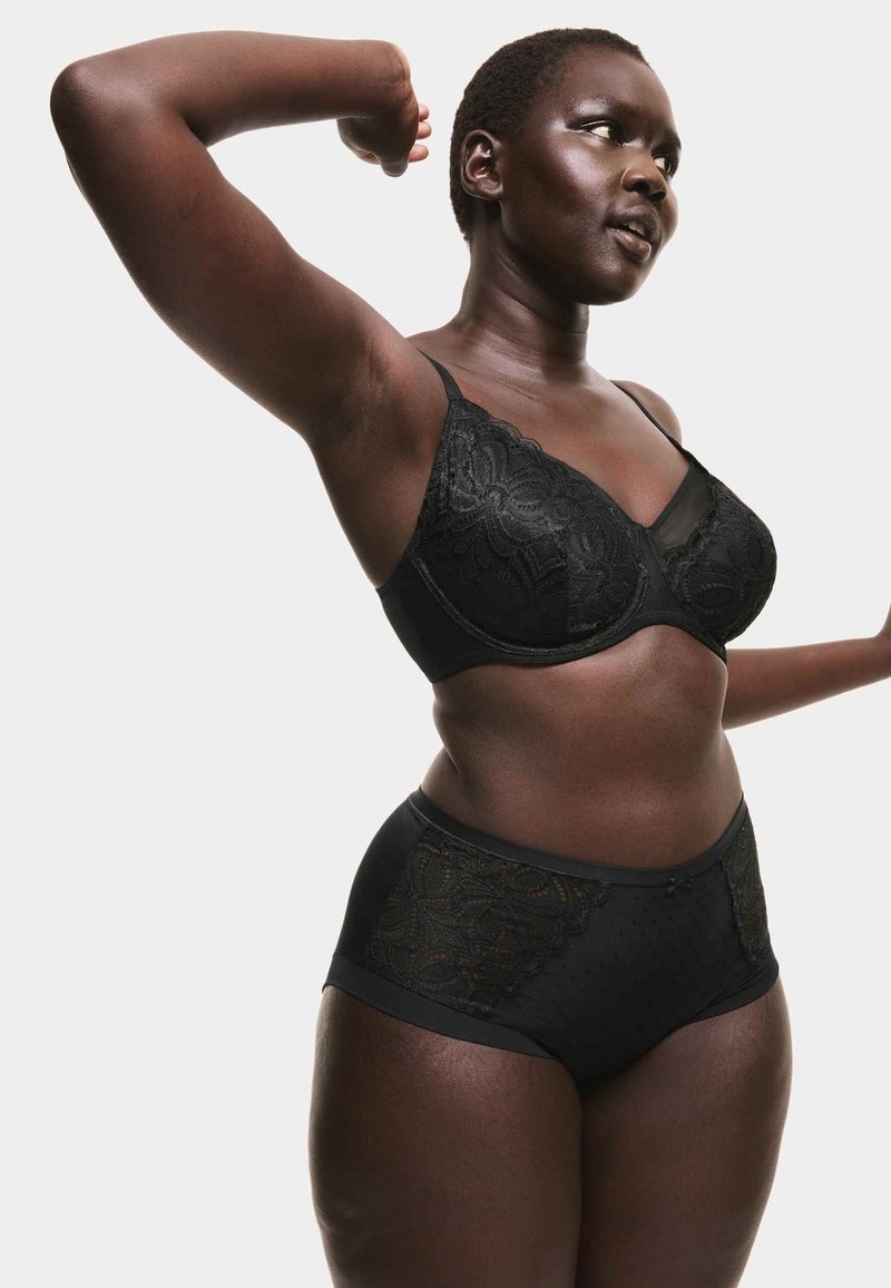 Sort blonder BH med gennemsigtigt netindlæg med blomsterprint. Matcher med højtaljede sorte trusser, også med blondeaccenter.