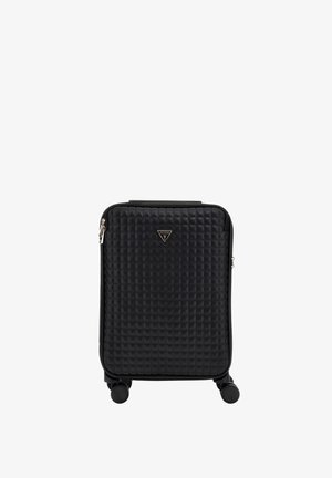 Valise rigide noire matelassée avec quatre roues, une poignée supérieure et une plaque triangulaire avec le logo Guess au centre avant.