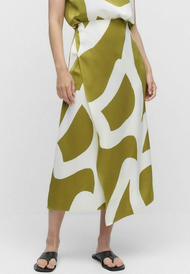 Olijfgroene en witte gestreepte rok met een asymmetrische onderrand, gemaakt van een gladde stof. G gedragen met zwarte sliding sandalen.