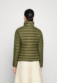 Olijfgroene pufferjack met een hoge kraag, horizontale stiksels en een oranje accentlabel op de linkerschouder. Glad, lichtgewicht stof.