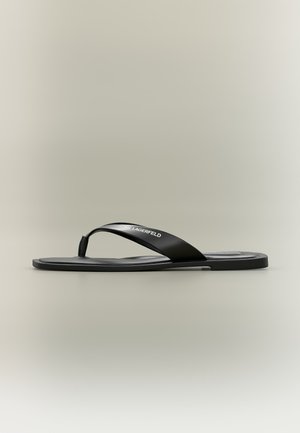 Zwarte rubberen teenslipper met een platte zool en brede band met het merk "Karl Lagerfeld", getoond op een neutrale achtergrond.