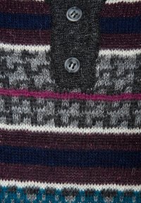Sweter dzianinowy z ciemno- i jasnoszarymi , głęboko burgundowymi, granatowymi i tealowymi paskami. Zawiera detale z guzikami przy dekolcie. Miękka tekstura.