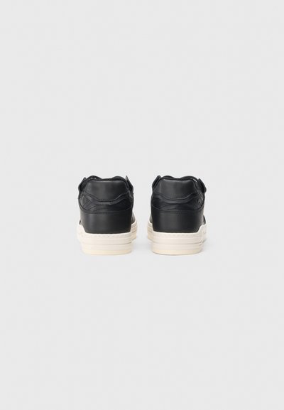 Czarne skórzane sneakersy o gładkiej fakturze, biała podeszwa środkowa i zaokrąglony obcas; mają przeszywaną konstrukcję i miękki kołnierz z tyłu.
