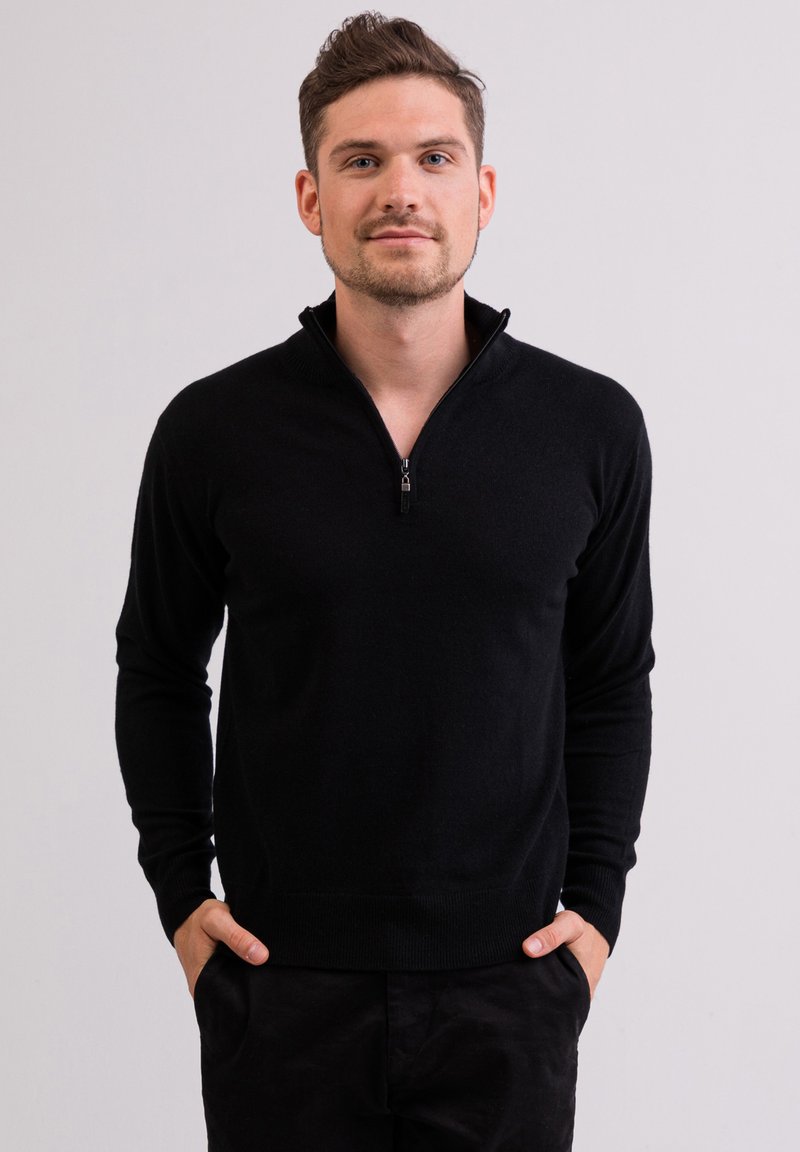 Schwarzer Pullover mit Reißverschlusskragen, langen Ärmeln und tailliertem Schnitt. Hergestellt aus weichem Material mit glatter Textur.