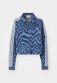 Kort denimjack met een blauw zigzagpatroon, witte gestreepte mouwen en een ritsluiting. Inclusief het Adidas-logo op de borst.