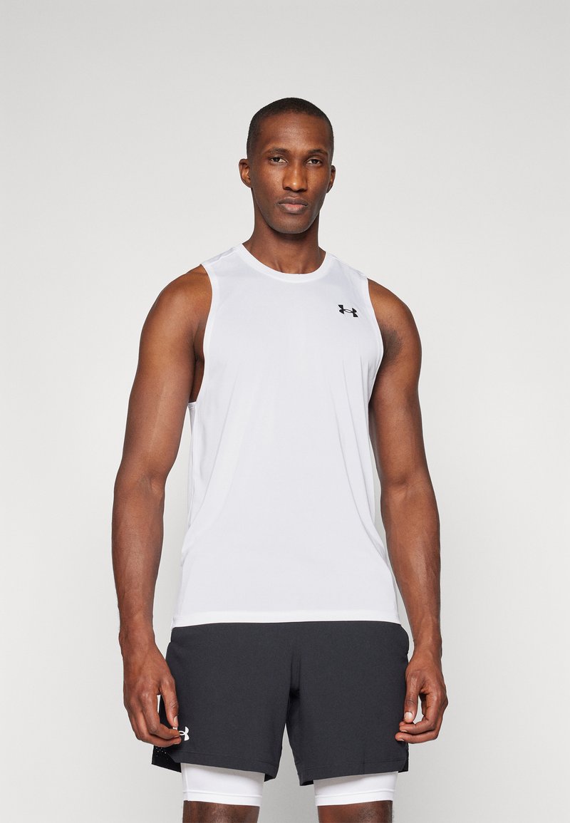 Débardeur de sport sans manches blanc avec un col rond et un petit logo noir sur la poitrine, associé à un short foncé.