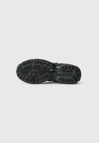 Semelle de chaussure de sport noire avec une surface en caoutchouc texturé présentant un motif de semelle en forme d'hexagone pour une meilleure adhérence et durabilité.