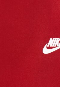 Tecido de algodão vermelho com o logotipo da Nike em branco. A textura é suave com um leve estiramento, característico de vestuário desportivo.