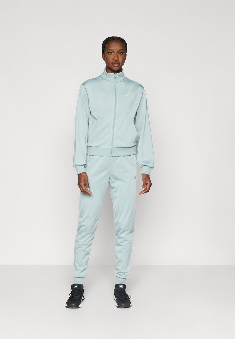 Αθλητική φόρμα σε ανοιχτό μπλε χρώμα από απαλό ύφασμα, με ζακέτα με φερμουάρ, ψηλό γιακά και ριμπ μανσέτες, συνδυασμένη με παντελόνι στο ίδιο σχέδιο.