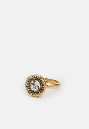 Goldring mit einem großen zentralen klaren Edelstein, umgeben von einem Kreis kleinerer klarer Steine auf einfachem Hintergrund.