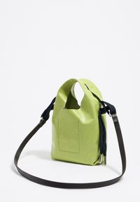 Zielona torebka z sztucznej skóry o teksturowanym wykończeniu, z unikalnymi uchwytami w kształcie wycięcia i długim, regulowanym paskiem w kolorze czarnym. Posiada tylną kieszeń.