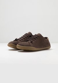 Chaussures en suede marron avec un profil bas, un bout rond et une semelle en caoutchouc texturé. Présentent un système de laçage et des accents de couture subtils.