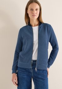 Veste zippée à rayures bleues avec un col et des poignets côtelés, présentant des rayures horizontales contrastantes et une texture lisse.