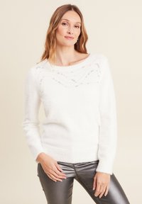 Weißer gestrickter Pullover mit weitem Rundhalsausschnitt, der ein strukturiertes Muster und leichte Verzierungen aufweist. Weicher, flauschiger Stoff mit langen Ärmeln.