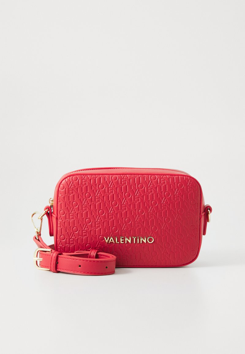 Sac bandoulière rouge avec motif de logo en relief. Accents en métal doré, bandoulière réglable, forme rectangulaire et fermeture éclair. Surface texturée.