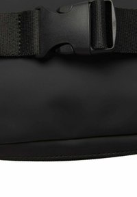 Borsa impermeabile nera con superficie testurizzata, ampia tracolla in nylon regolabile e chiusura a fibbia in plastica, progettata per resistenza e utilità.