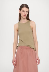 Top senza maniche khaki con texture a costine e collo rotondo, abbinato a una gonna leggera rosa chiaro con vita elasticizzata.