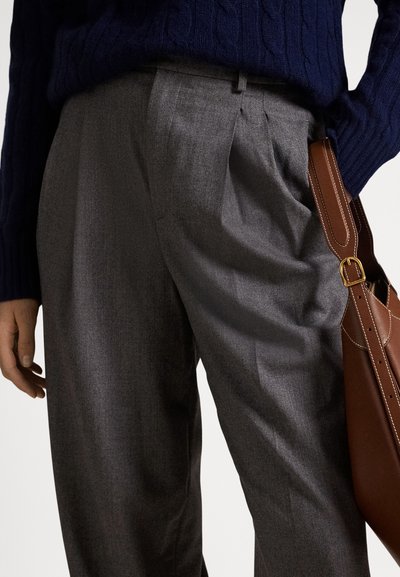 Γκρι πλεκτό παντελόνι με ρεβέρ, από υφή υφάσματος, σε συνδυασμό με μπλε-σκούρο πουλόβερ με ανάγλυφο σχέδιο και καφέ δερμάτινη τσάντα ώμου.