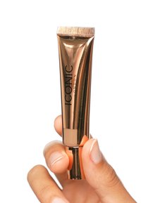 Metallisk roségullrør av ICONIC London-produkter holdt i en hånd. Har en vribar bunn og en klar panel som viser innholdet.