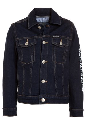 Veste en denim bleu foncé avec boutons argentés, deux poches avant à rabat, coutures contrastées, et "Calvin Klein Jeans" imprimé le long de la manche droite.