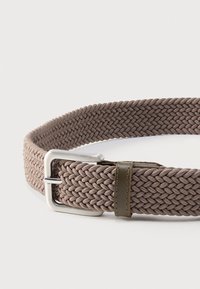 Πλεκτή ζώνη από ύφασμα σε απόχρωση ταφ με ασημί μεταλλική αγκράφα και δερμάτινο λουράκι σε ελιά πράσινο χρώμα, σε λευκό φόντο.