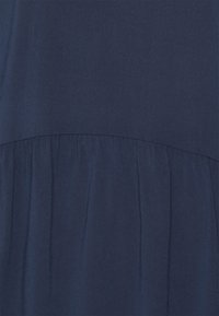 Vestido azul marinho com um tecido texturizado, parte inferior em forma de saia rodada com uma linha de cintura franzida e um design superior liso.