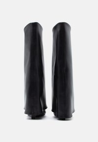 Fekete bőrből készült térdig érő csizma, strukturált sziluettel, sima textúrával és minimalista dizájnnal. Vékony varrással és kis sarokkal rendelkezik.