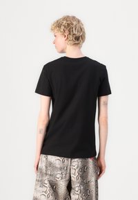 Svart bomull t-skjorte med korte ermer, rund hals og rett snitt. Bakvinduet har et minimalistisk design uten grafikk.
