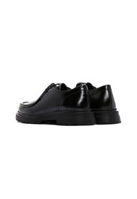 Scarpe in pelle nera con finitura lucida, punta arrotondata, dettagli testurizzati sulla parte superiore e suola in gomma spessa.
