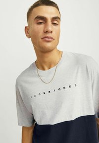 Hall hall ja navy värviblokiga lühikeste varrukatega t-särk, millel on must "JACK & JONES" logo, kerge kangas, ümmargune kaelus ja mugav lõige.