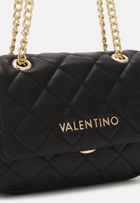 Schwarze gesteppte Lederhandtasche mit einem goldenen Kettenriemen und goldenen Hardware-Elementen. Verfügt über einen Klappenverschluss und ein geprägtes Logo auf der Vorderseite.