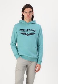 Turkusowa bawełniana bluza z kapturem z przednią kieszenią, elastycznymi mankietami oraz czarnym nadrukiem "PME Legend American Classic" i grafiką skrzydeł na klatce piersiowej.