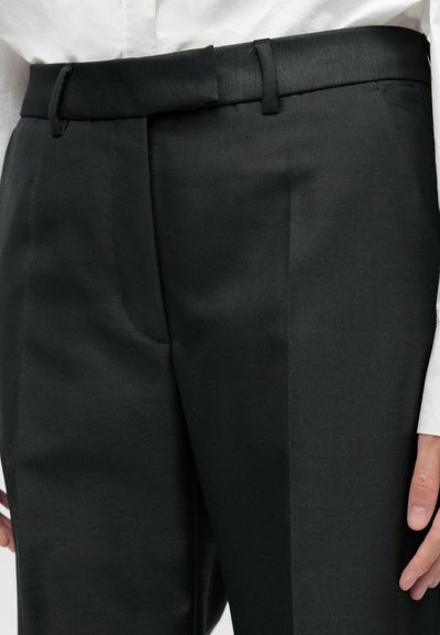 Zwarte, op maat gemaakte broek met een gestructureerde tailleband en lussen voor een riem, met een gladde textuur en gestreken plooien aan de voorkant.